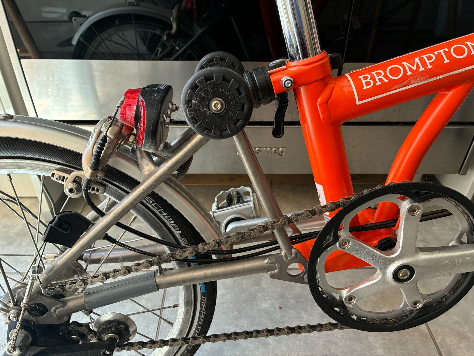 Brompton M3L Superlight Titanium  3 Speed in orange with front Ortlieb bag